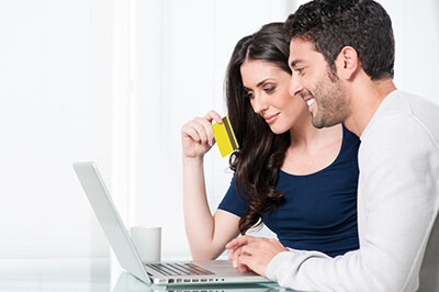 Happy Man and Woman Smiling at Their Laptop Computer With Credit Card