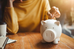 woman putting money into piggy bank 